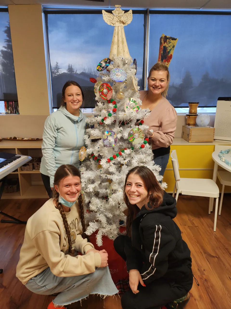 Educators smiling together beside a decorated holiday tree