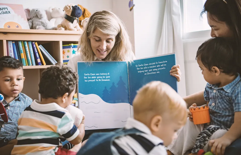 An educator reading a picture book to a group of young children