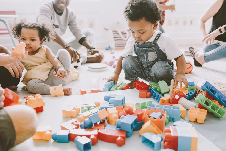 Toddlers building with colourful blocks on the floor