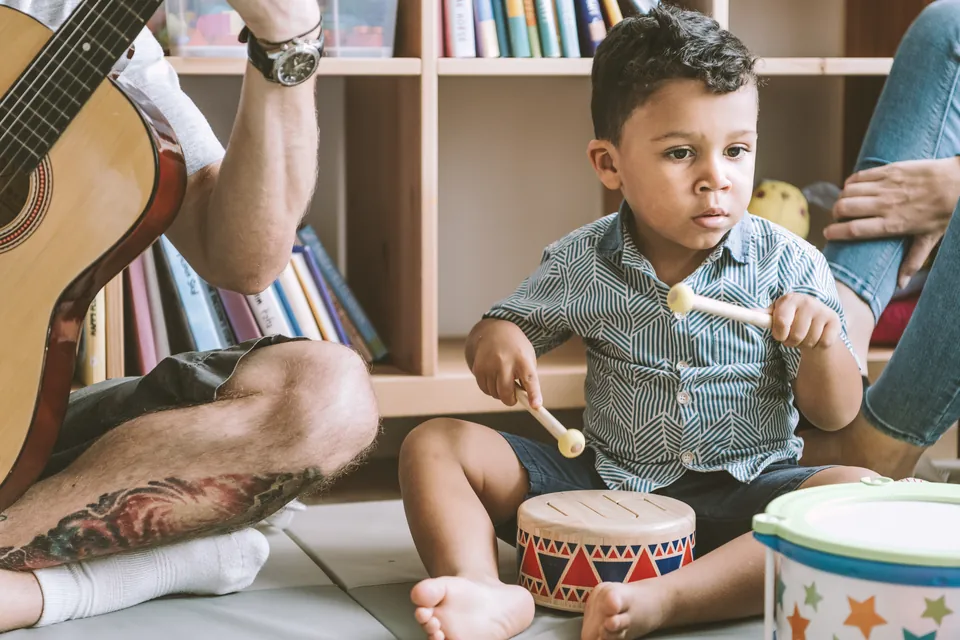 A young boy playing a drum during music time