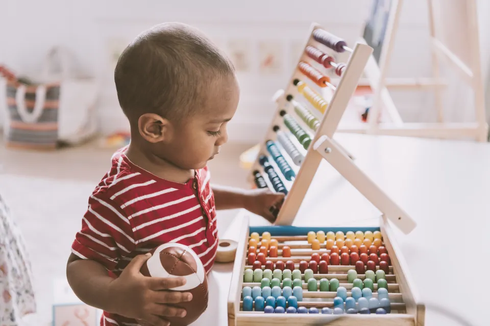 A toddler exploring a colourful wooden abacus